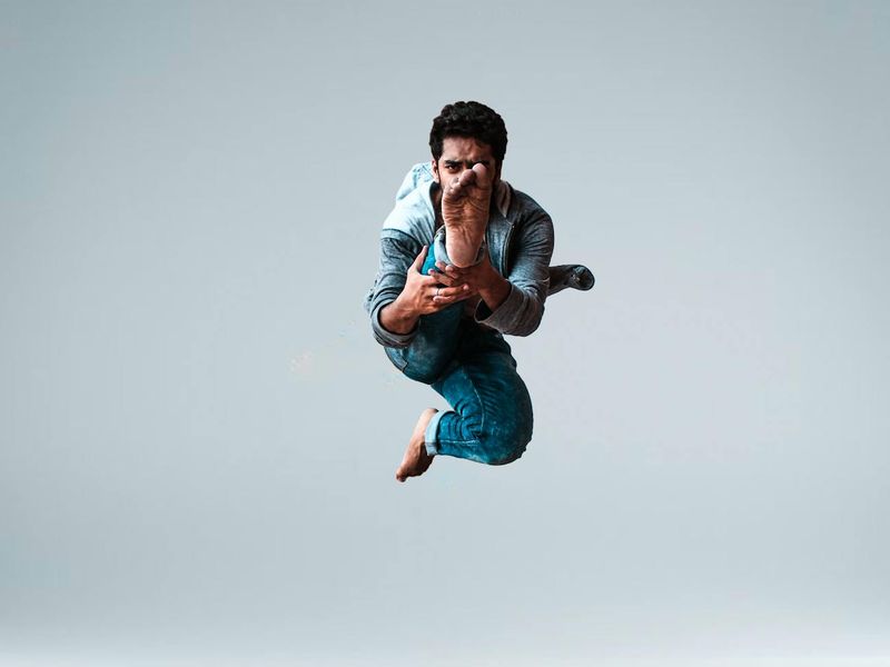 Person captured mid-jump in a spacious, well-lit studio.
